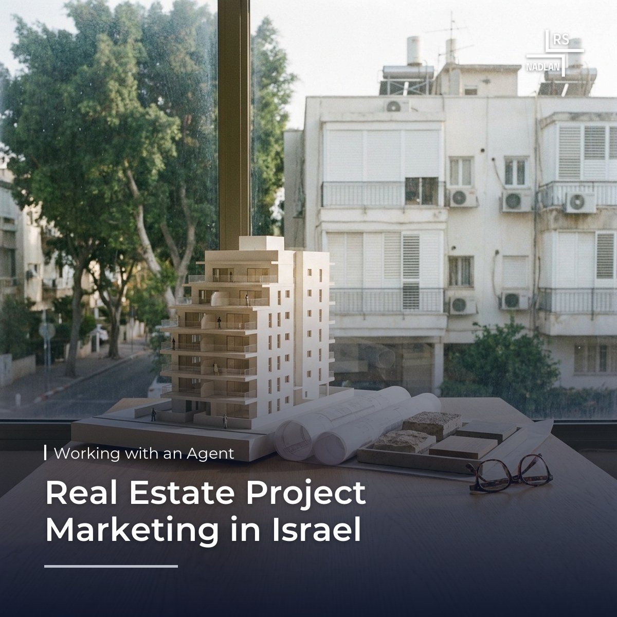 Architectural model of a new residential building and apartment floor plans on a table in a sales office in north Tel Aviv